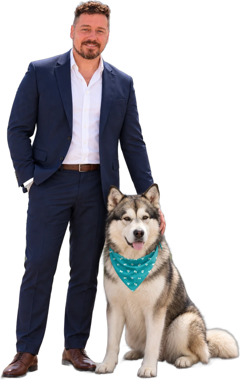 Adam Pierce in a navy suit standing beside his Alaskan Malamute, Aleksandr